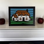 Stylised faux stained‑glass A4 MDF panel depicting a cottage with thatched roof, white walls, and geometric sky and field shapes.”