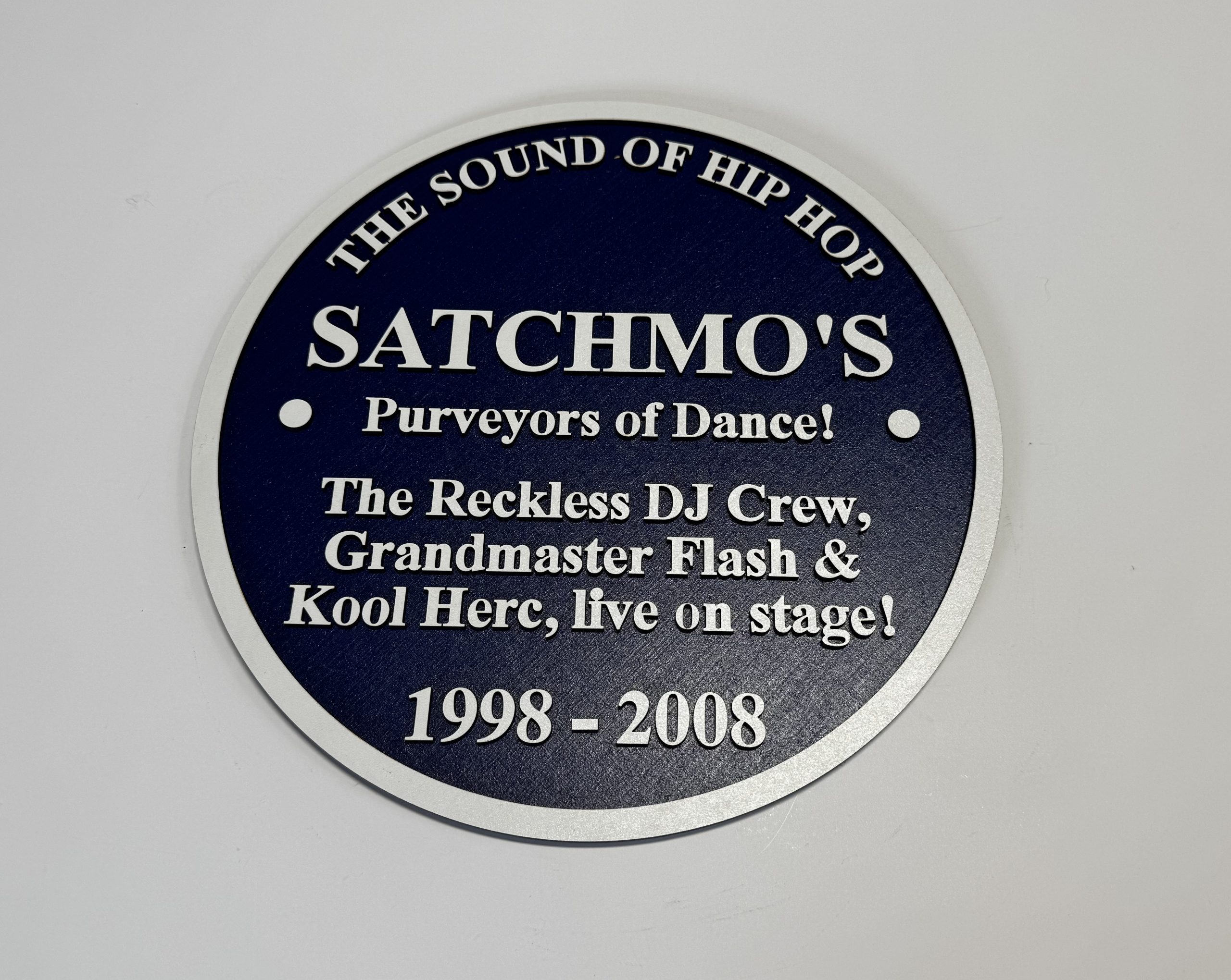 Hip‑Hop Commemorative Plaque – Satchmo’s / Grandmaster Flash / Kool Herc - Boon Hill Designs - Custom Plaques, Signs & Gifts Hip-hop commemorative plaque featuring Satchmo’s, Grandmaster Flash and Kool Herc in white text on a dark blue circular design.